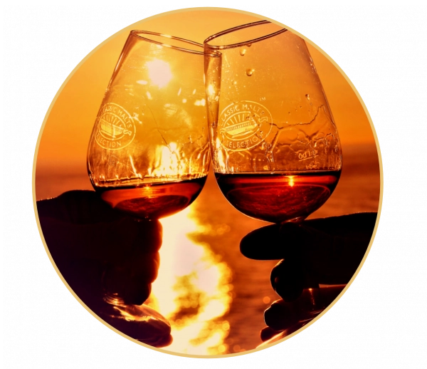 Foto von zwei Whiskygläsern vor einem wolkenfreien Sonnenuntergang auf dem Meer.
